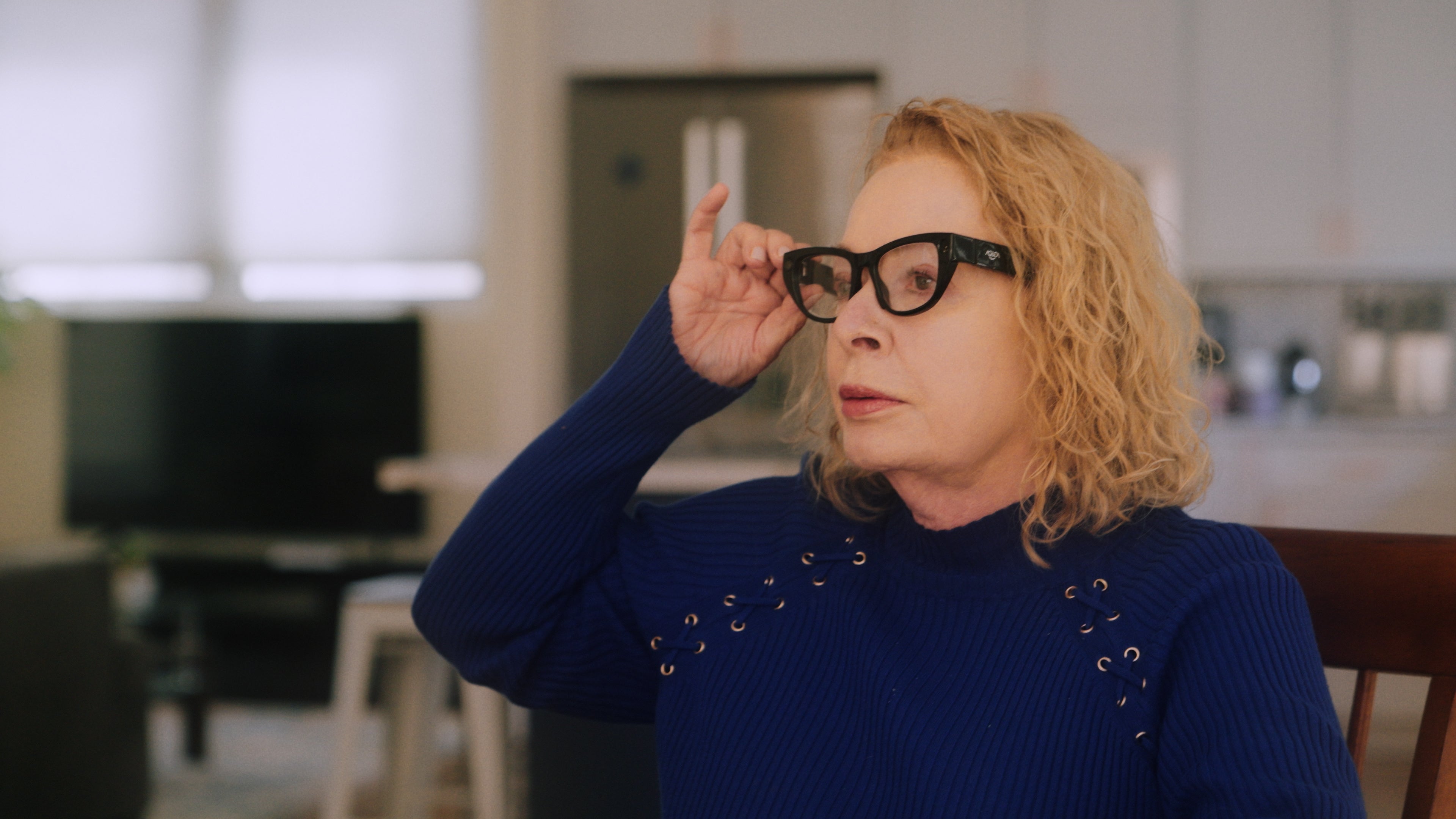 Image: Woman adjusting glasses in a kitchen setting